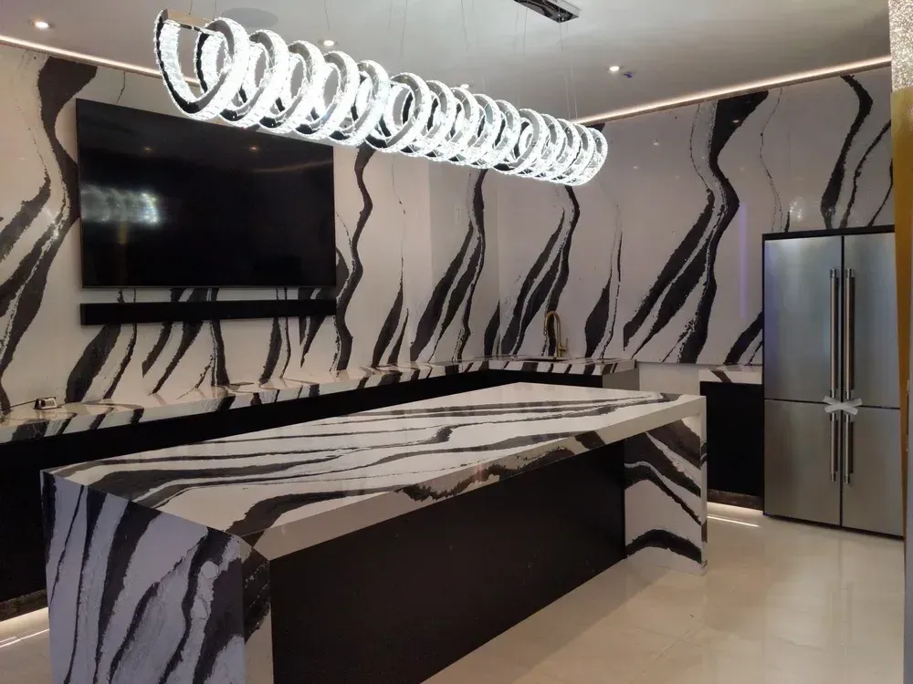 Modern kitchen with black-and-white wavy wall design, island counter, pendant lights, and stainless steel fridge