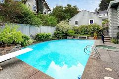 A large swimming pool with a diving board in the backyard of a house.