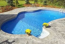 A large swimming pool surrounded by concrete and flowers