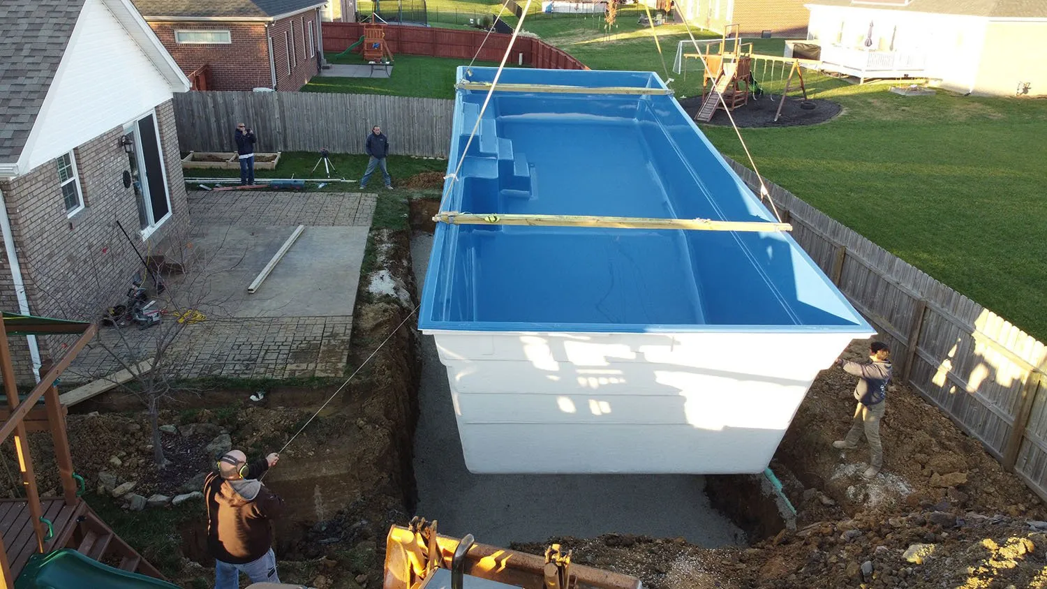 A large blue and white swimming pool is being built in a backyard.