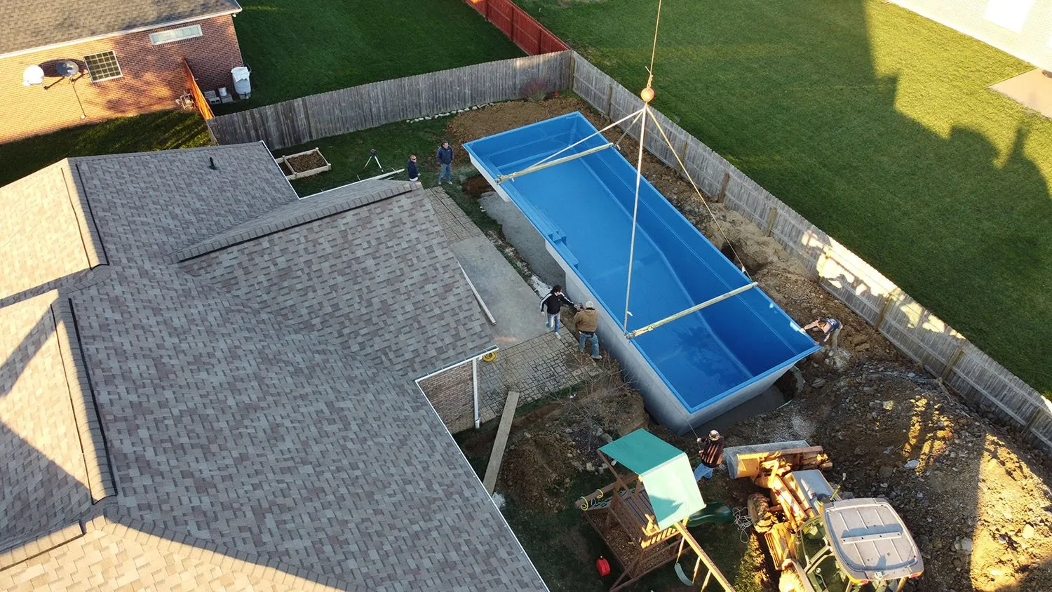 An aerial view of a swimming pool being built in a backyard.