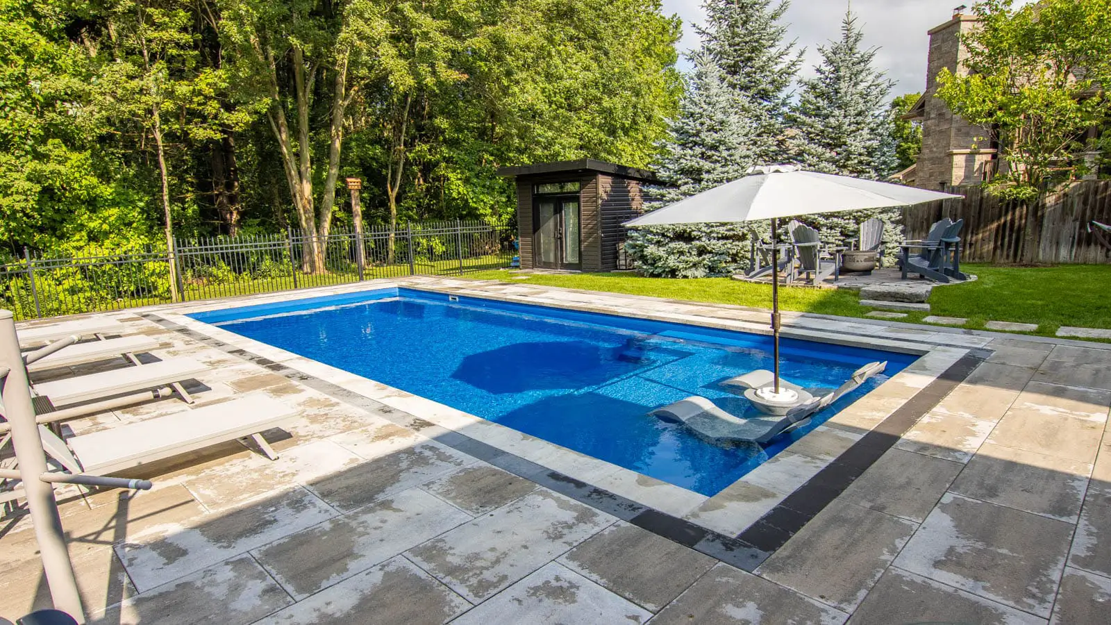 There is a large swimming pool in the backyard with a white umbrella.