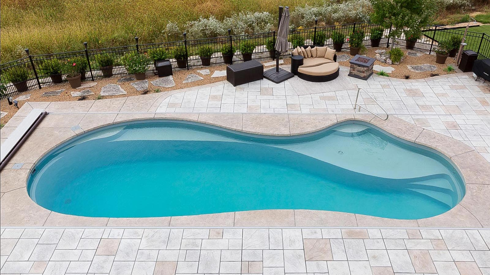 A large swimming pool is sitting on top of a brick patio.