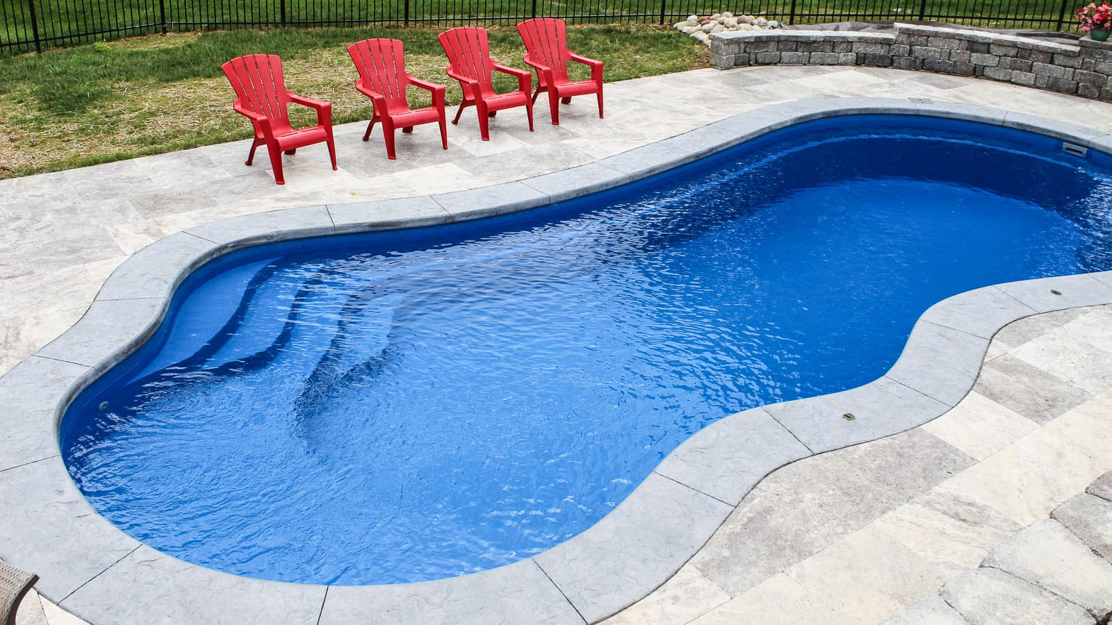 A large swimming pool with red chairs around it