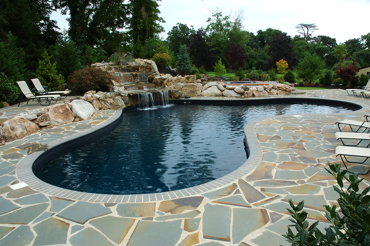 A large swimming pool with a waterfall in the backyard