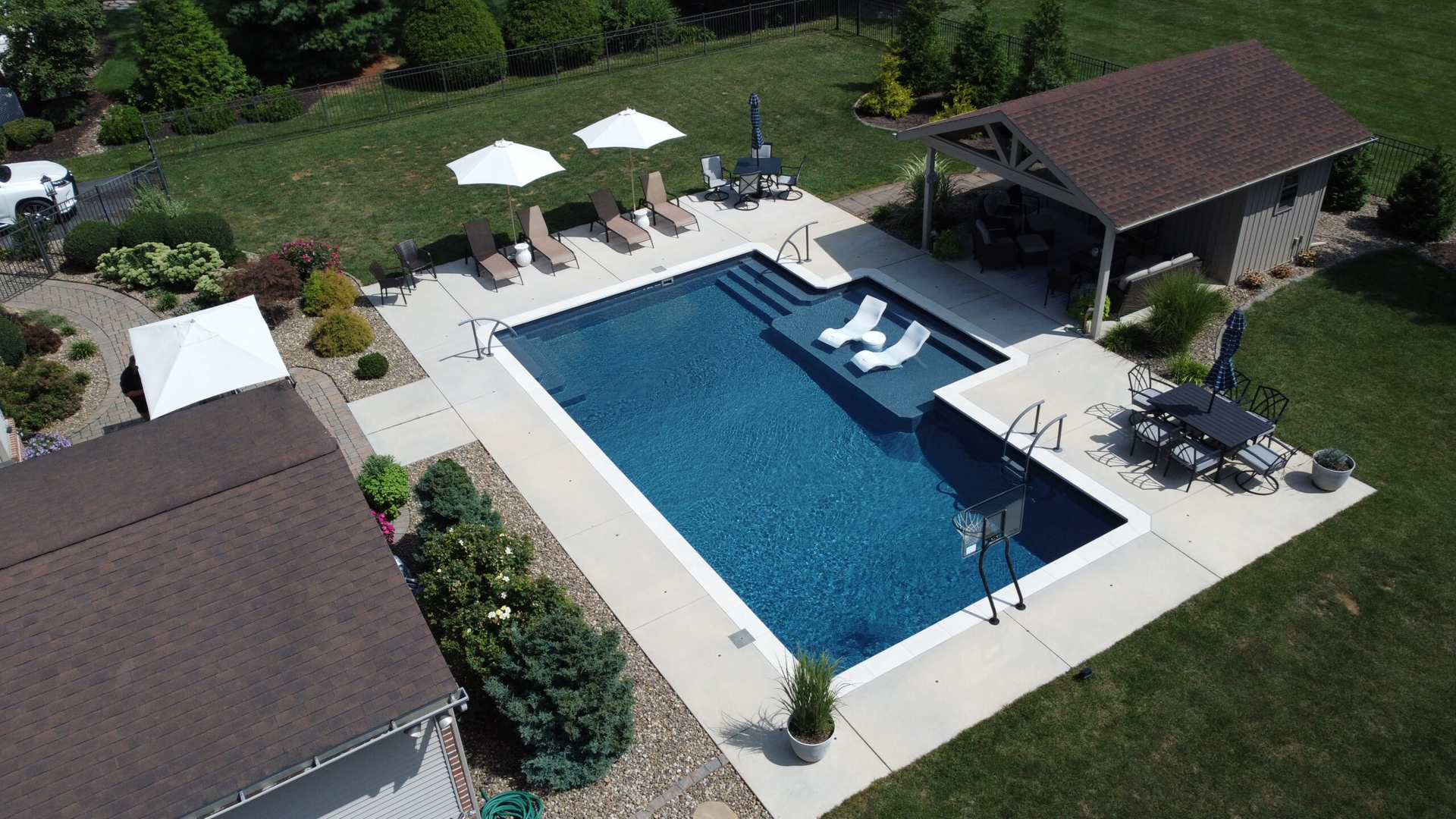 An aerial view of a large swimming pool surrounded by lawn chairs and umbrellas.