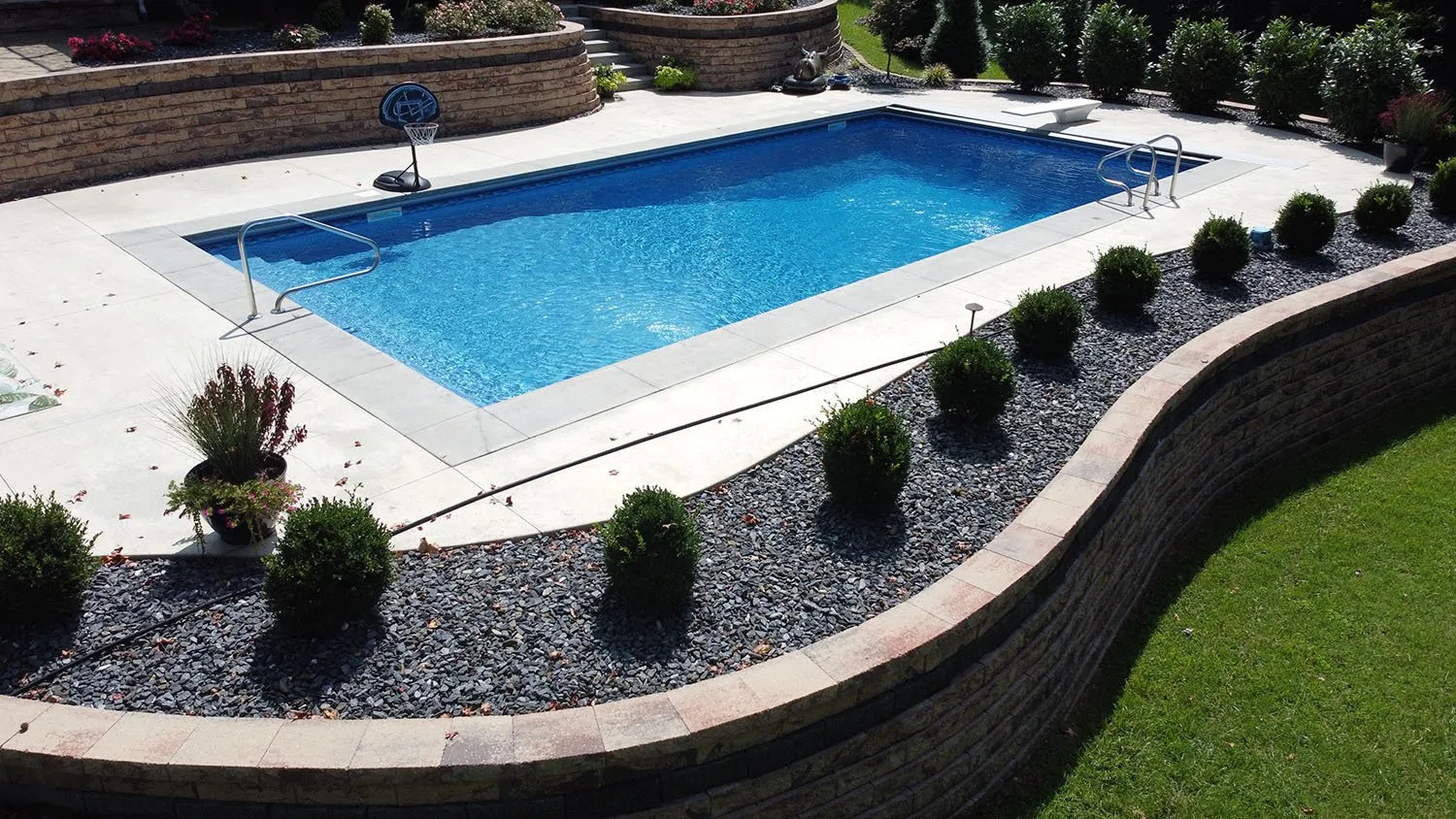 A large swimming pool surrounded by bushes and rocks
