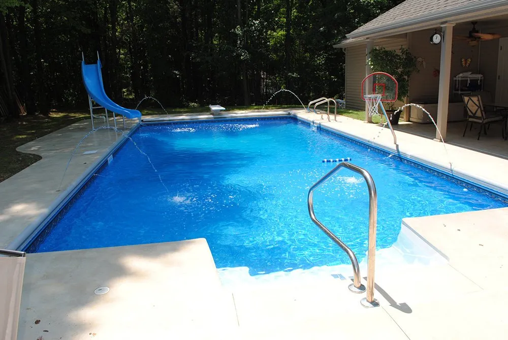 A large swimming pool with a slide in the backyard