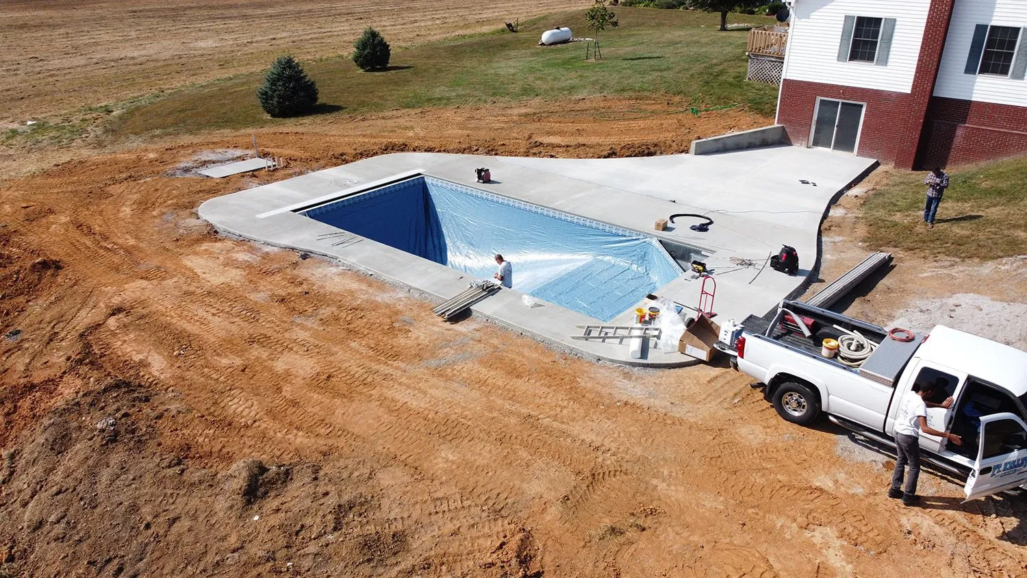 An aerial view of a swimming pool being built next to a house.