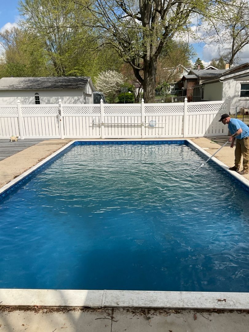A man is standing next to a large swimming pool.