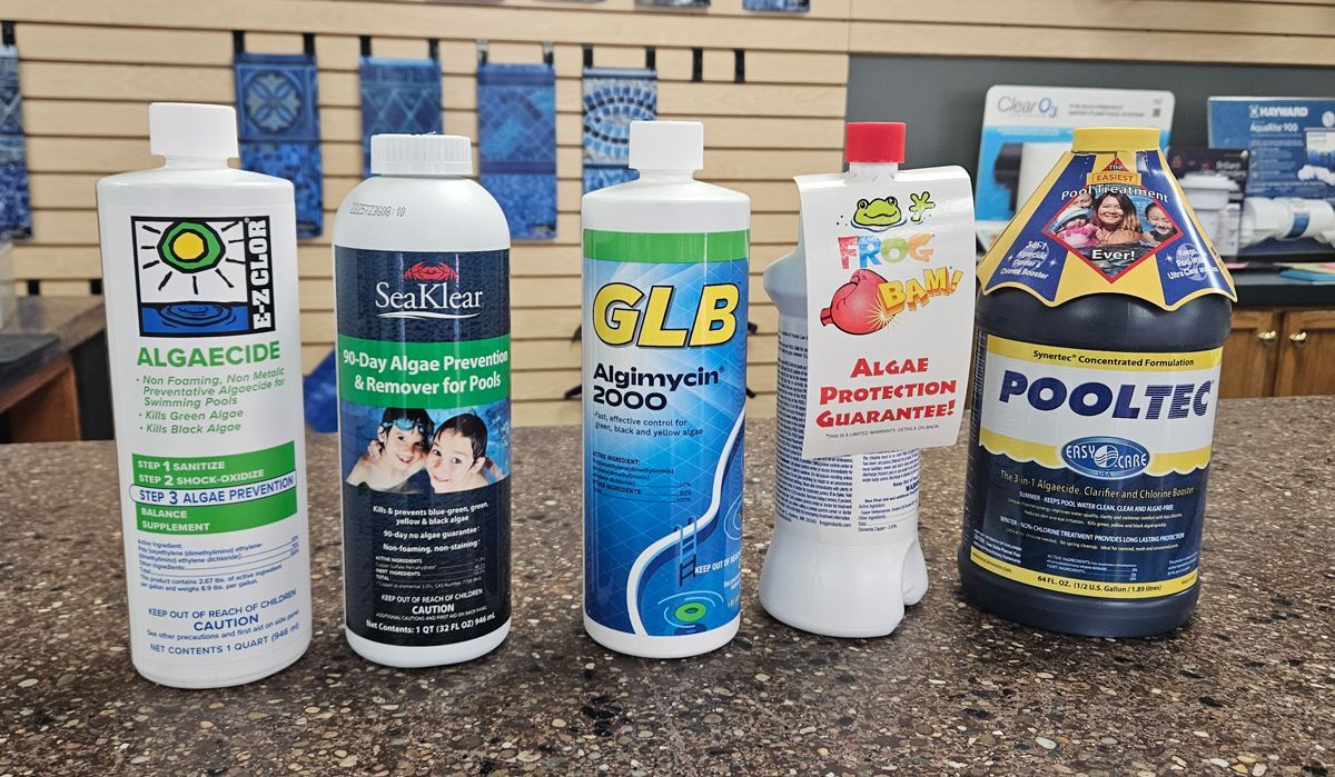 A group of bottles of pool chemicals are sitting on a counter.