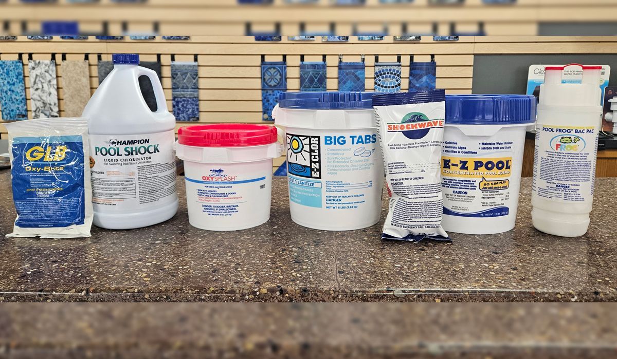 There are many different types of pool chemicals on the counter.