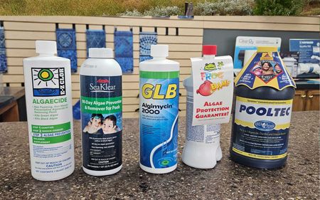 A group of bottles of swimming pool chemicals are sitting on a counter.