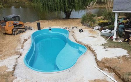 A large blue swimming pool is being built in a backyard.