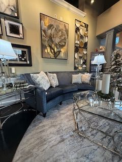 A living room with a curved couch and a glass coffee table.