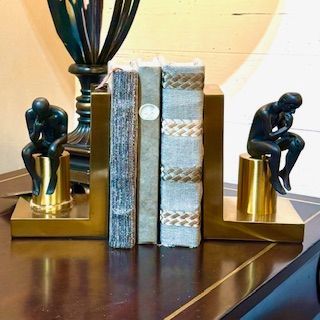 A pair of bookends with statues of men sitting on them