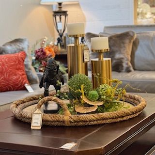 A coffee table with a rope tray filled with flowers and candles