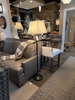 A living room with a couch , chair , table and lamp.