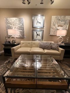 A living room with a couch , coffee table , and paintings on the wall.