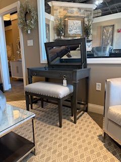 A vanity with a mirror and a bench in a living room.