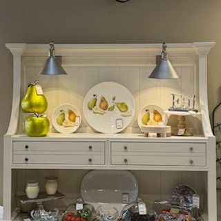 A white hutch with plates and fruit on it