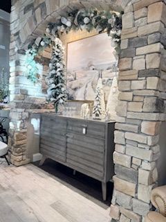 A living room with a stone fireplace and a wooden dresser.