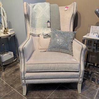 A white chair with a pillow and a blanket on it