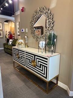 A black and white dresser with a mirror above it in a living room.