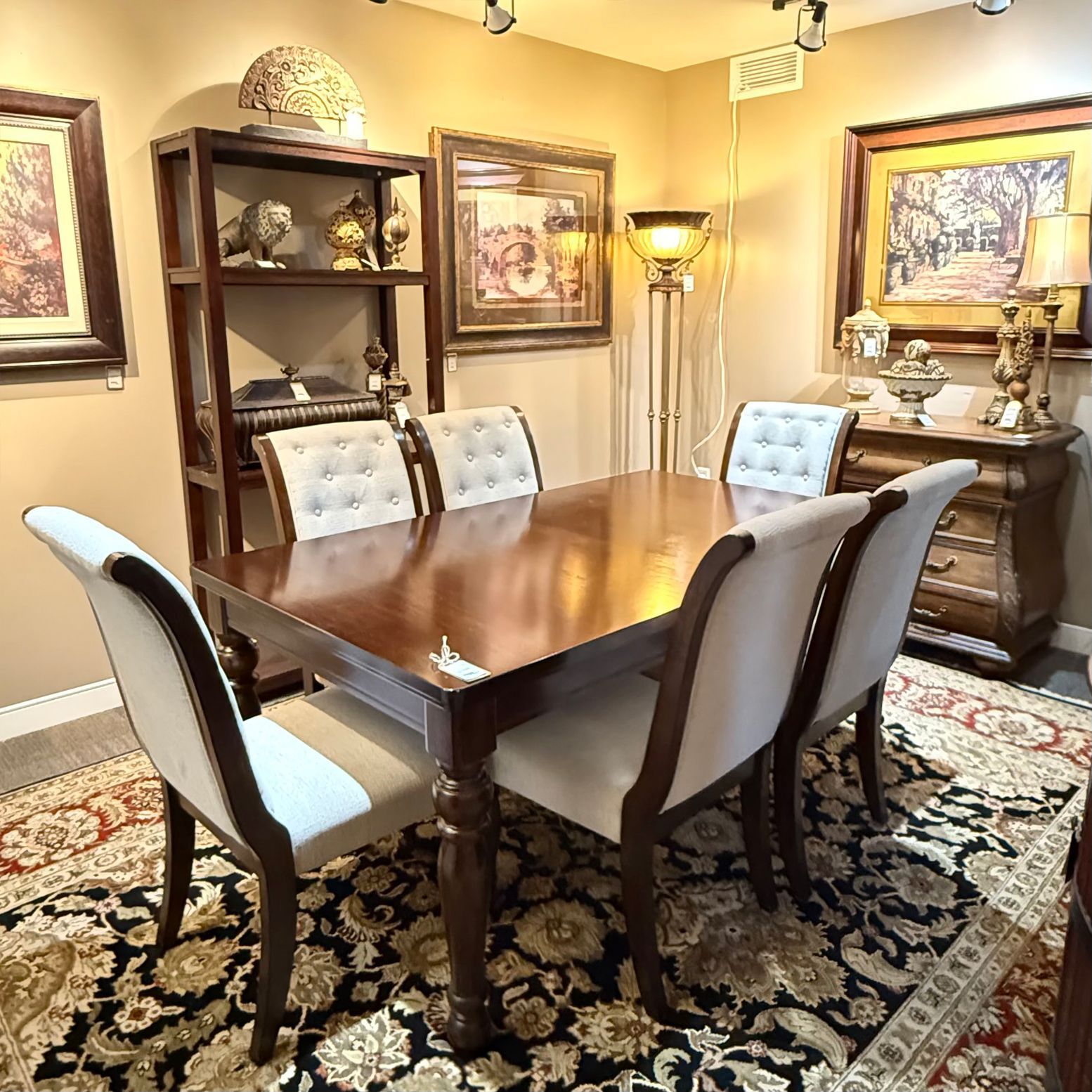 Dining room with table, six chairs, rug, artwork, and a cabinet.