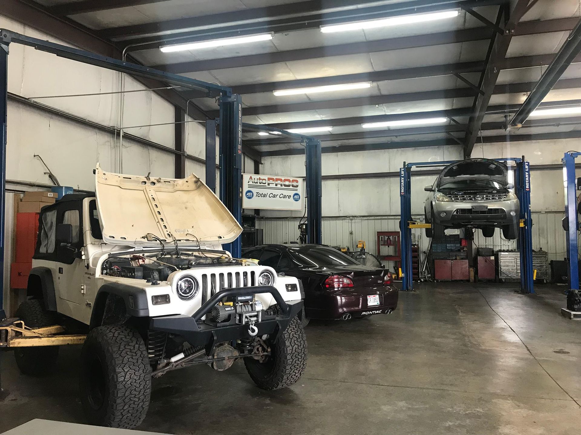 White Nissan truck with its hood open, in a repair shop.