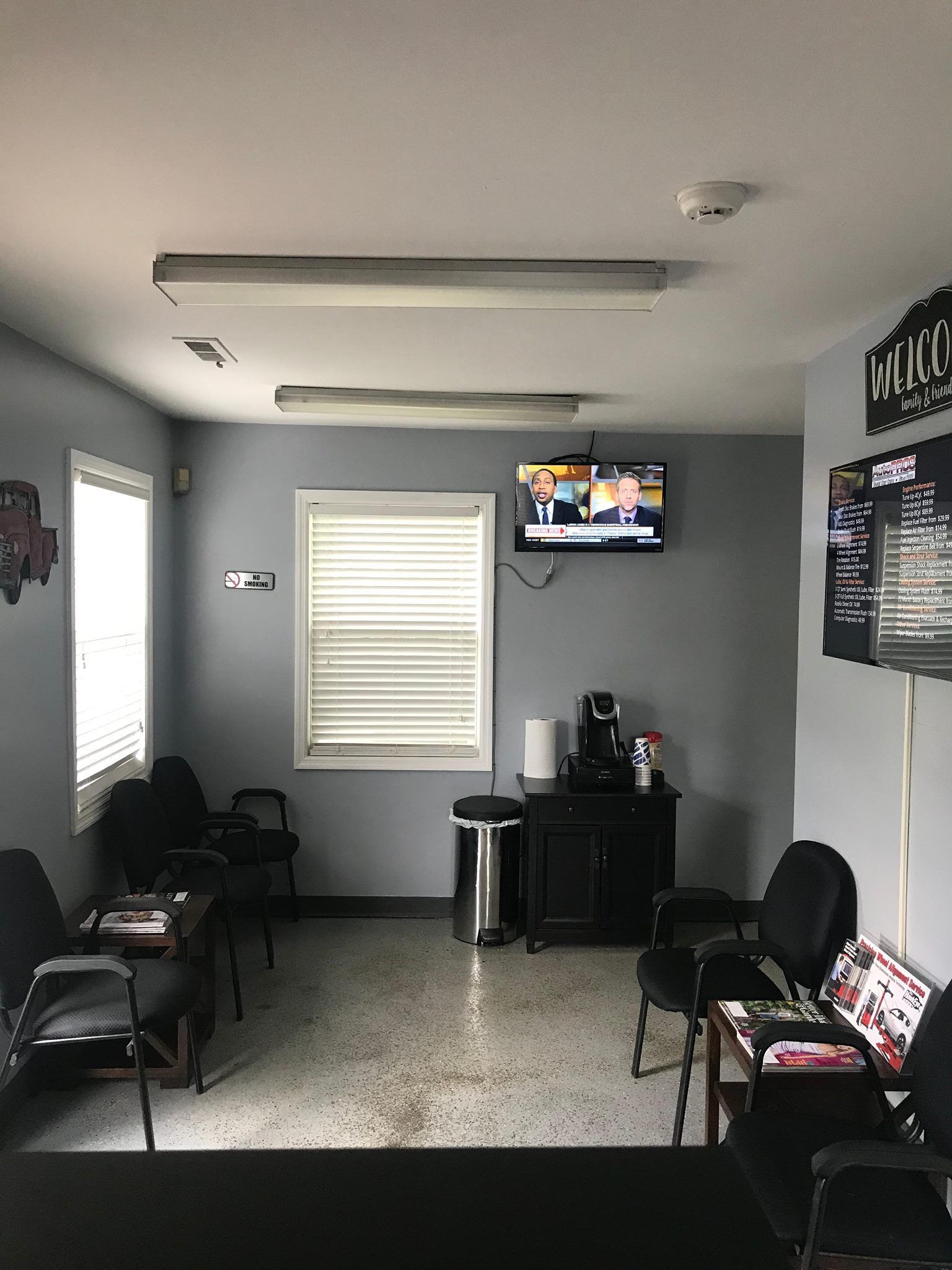 Waiting room with chairs, a TV, a coffee station, and a window with blinds.