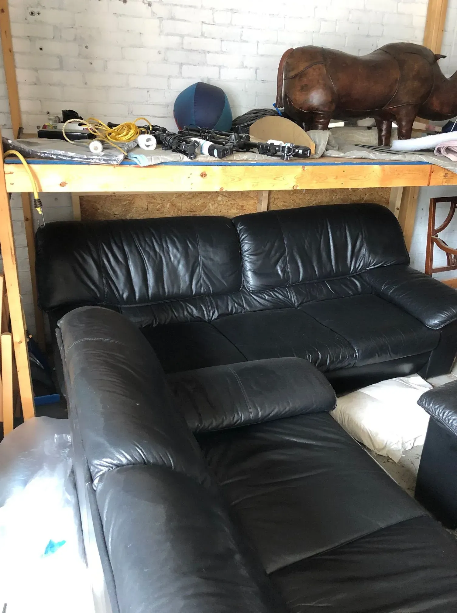 Black leather sectional sofa in a room with a wooden table and decorative objects on shelves.