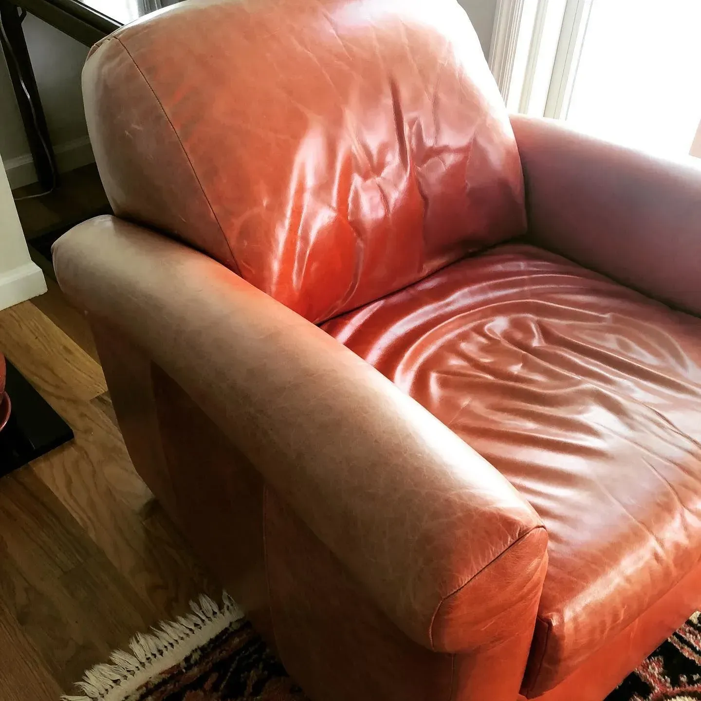 Red leather armchair beside a window in a sunlit room.