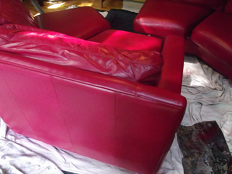 Red leather chairs piled and draped with white sheets in a cluttered room