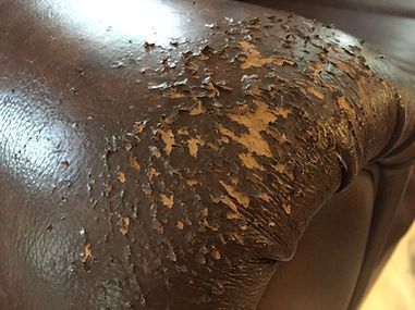 Close-up of a brown leather chair with peeling and scuffed surface on the seat corner