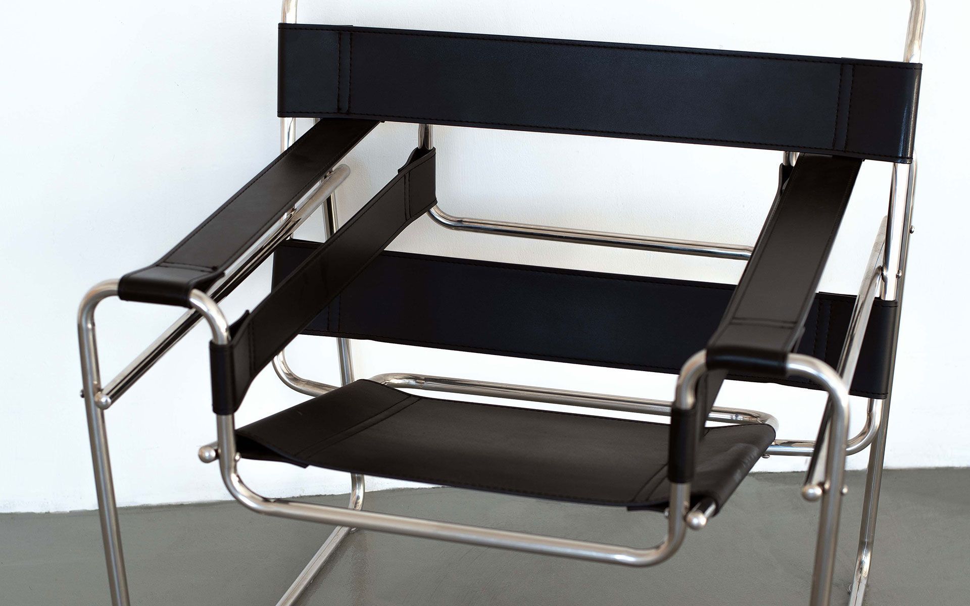 Black modern armchair with metal frame and black cushions on a white background