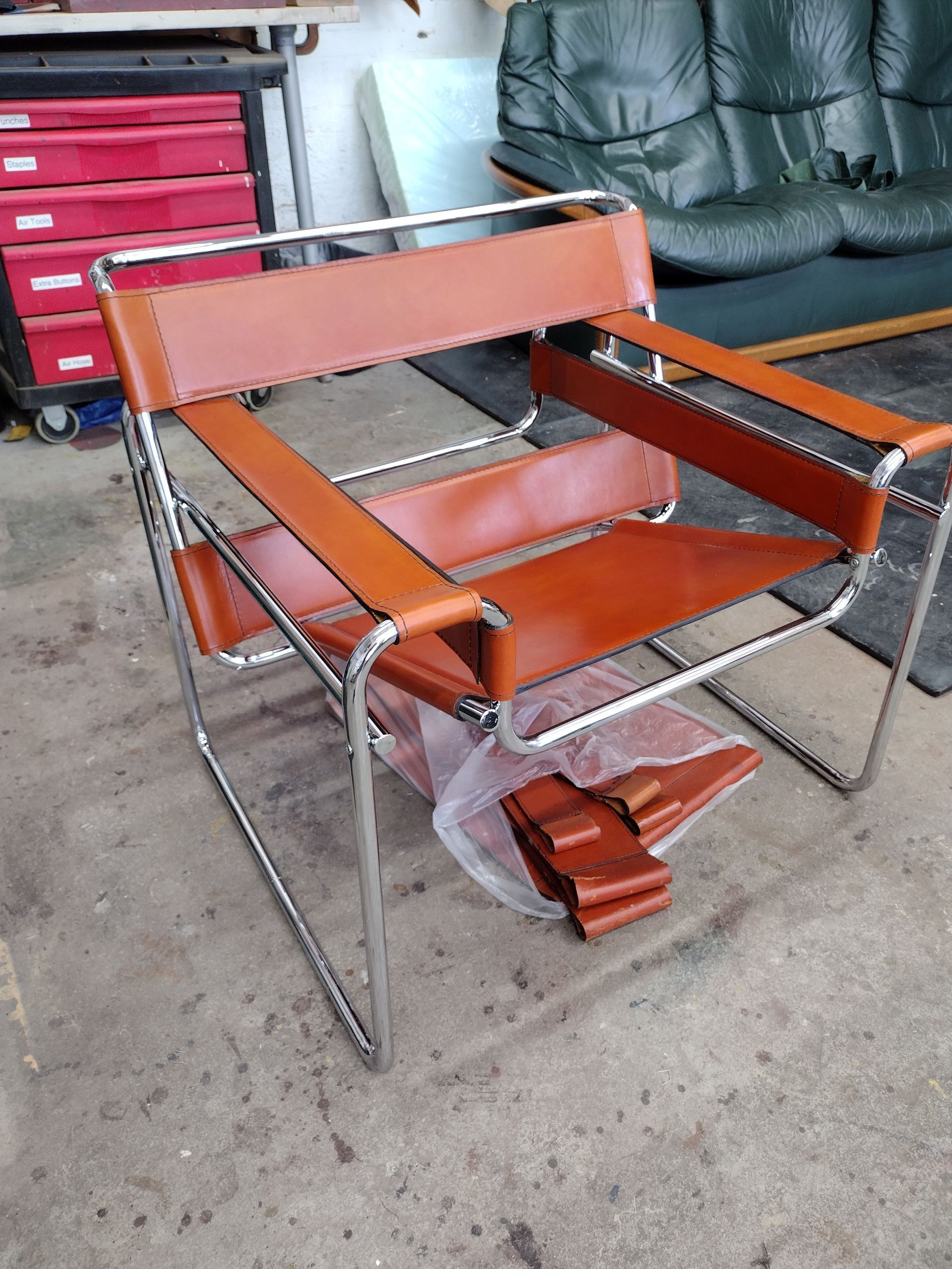Orange and chrome folding lawn chair in a garage, with another chair stacked beneath it.