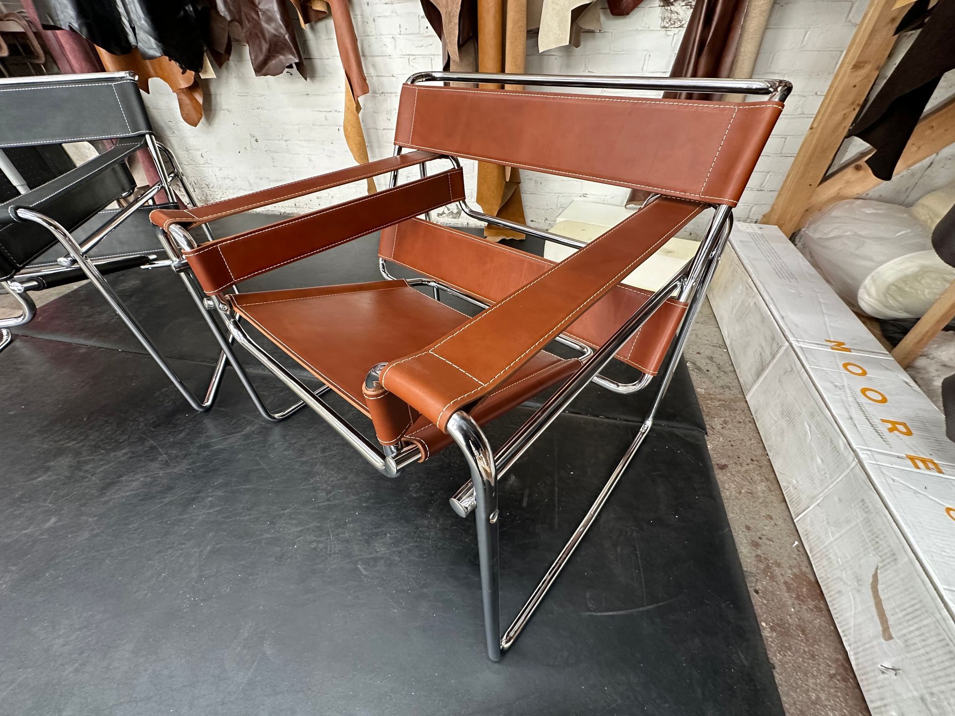 Brown leather folding chair in a workshop or storage area, with chrome metal legs and frame