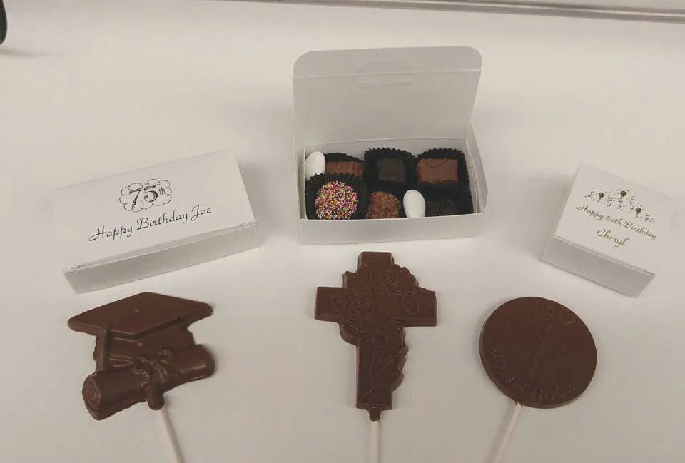 A box of chocolates with a graduation cap , cross , and circle on a stick.