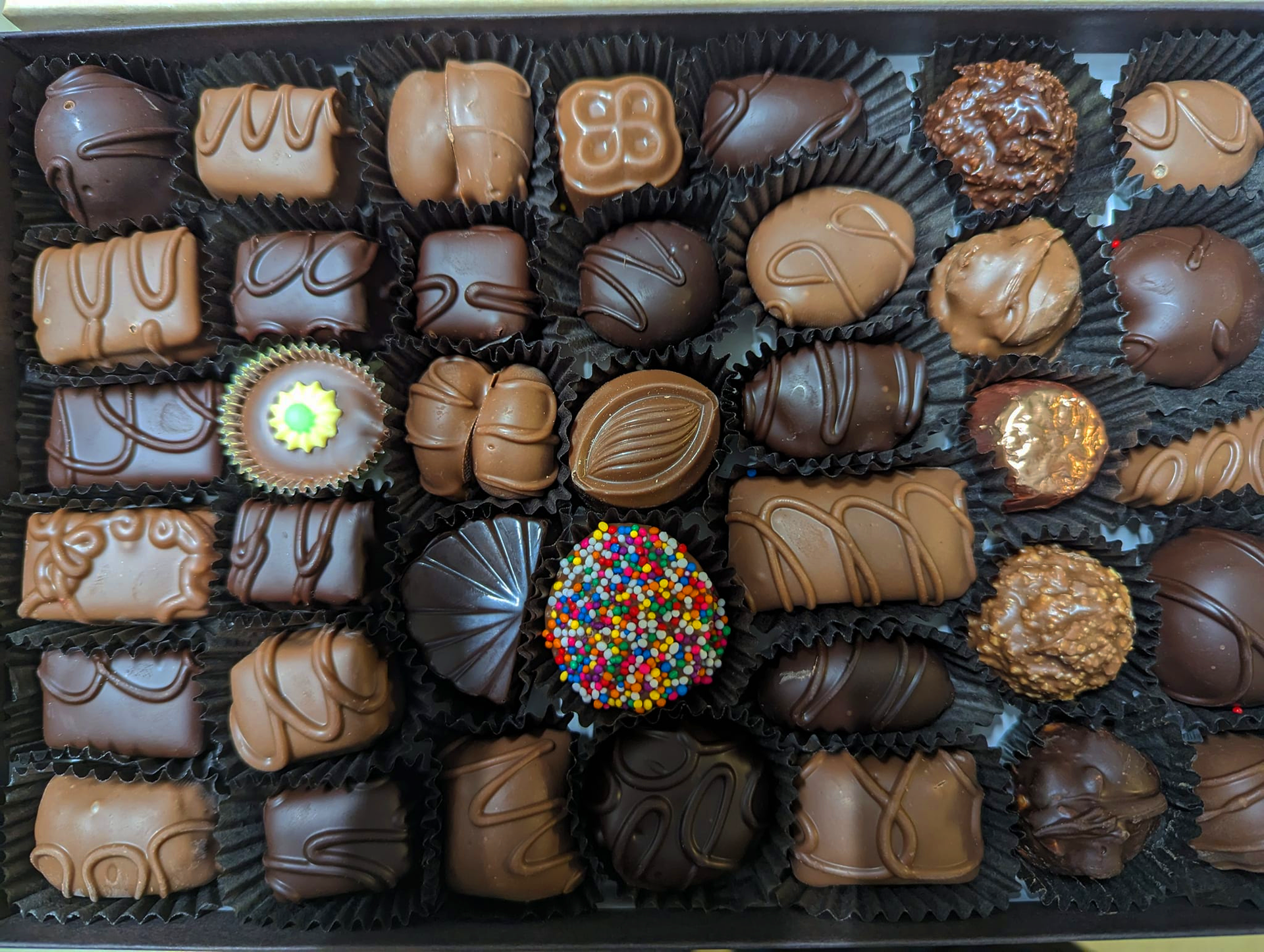 A box of chocolates with a sprinkle in the middle