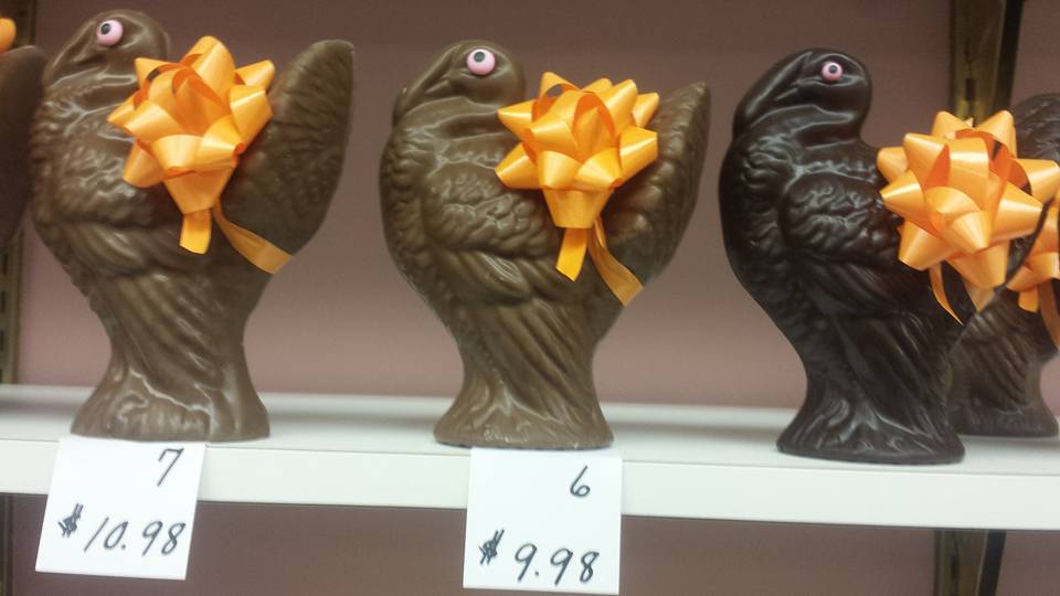Three chocolate turkeys with bows on them are on a shelf