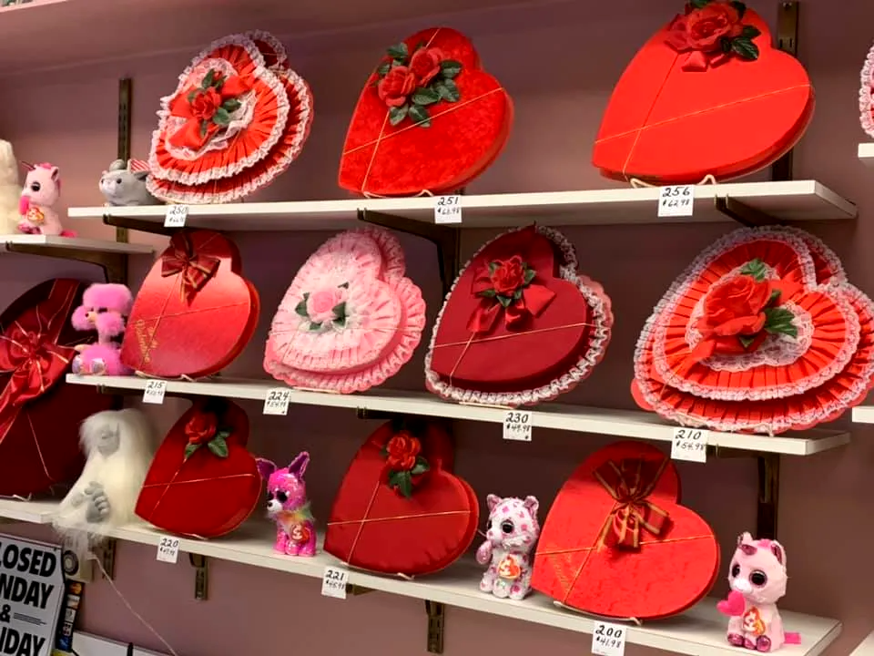 A shelf filled with heart shaped boxes and stuffed animals.