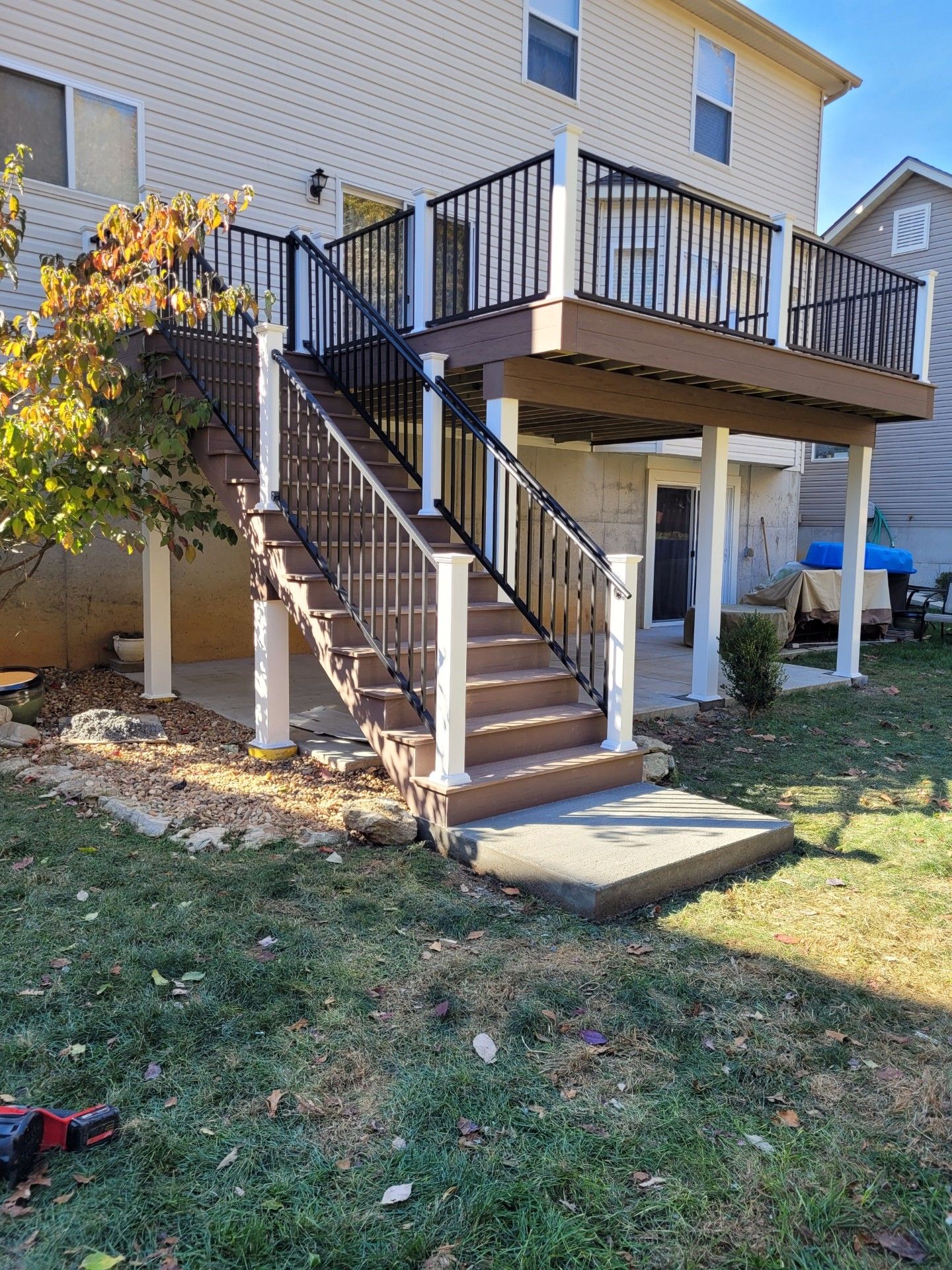 a deck with stairs leading up to it and a house in the background