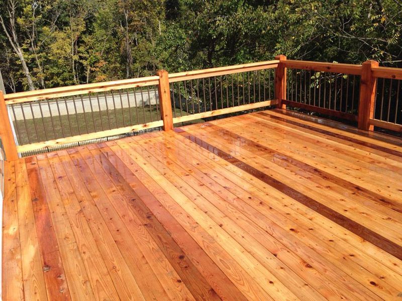a wooden deck with a railing and trees in the background