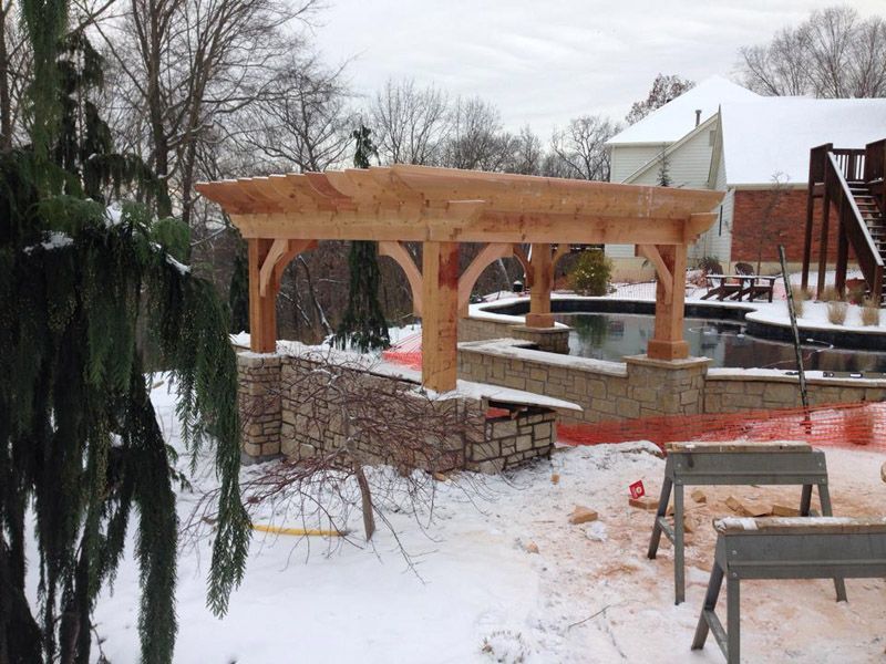 a wooden pergola is being built in the snow near a pool