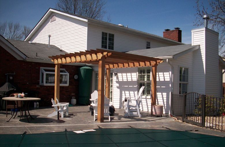 the backyard of a house with a pergola and chairs