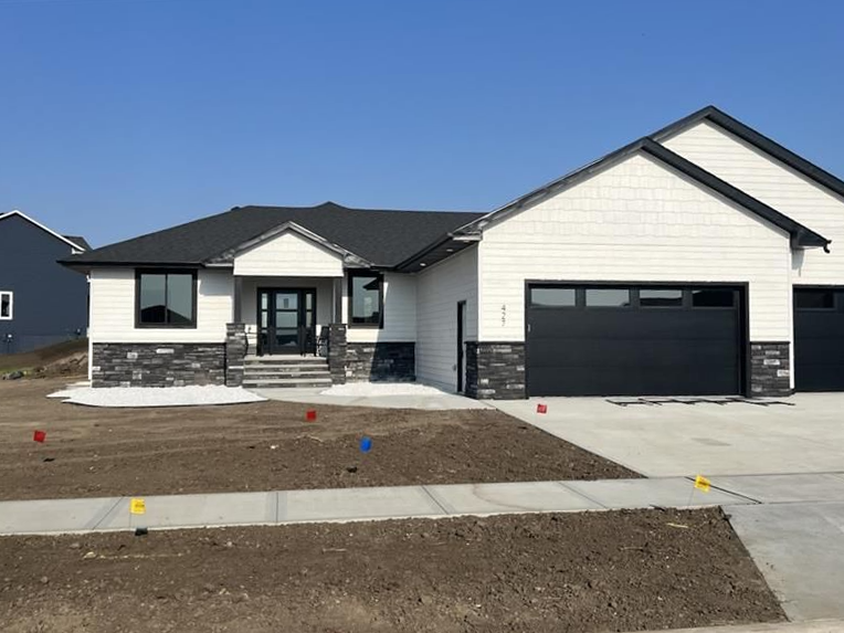 A white house with a black garage door and a black roof