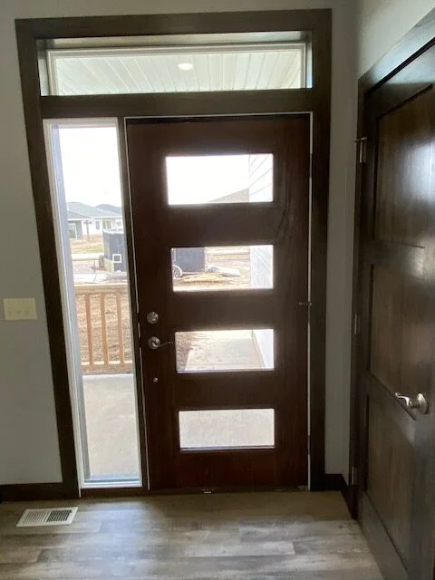 A wooden door with four square windows in a hallway.