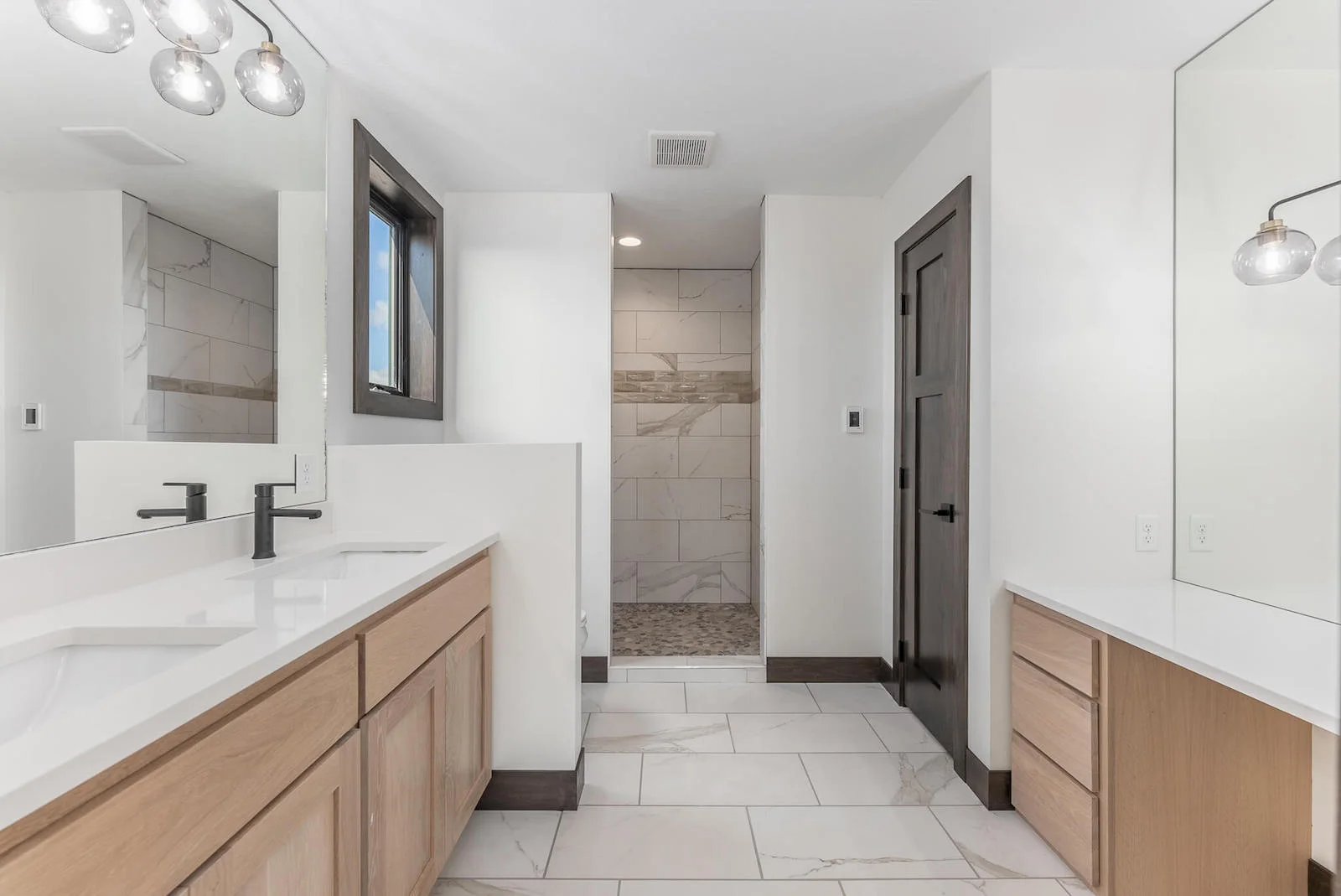 A bathroom with two sinks and a walk in shower.
