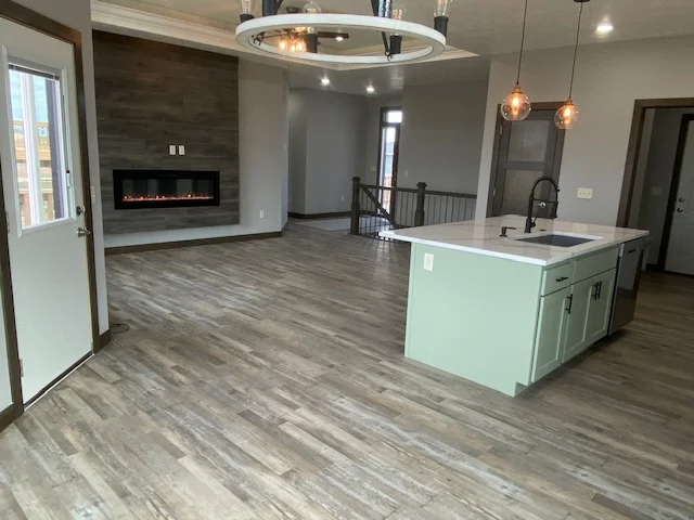 A kitchen with a green island and a fireplace